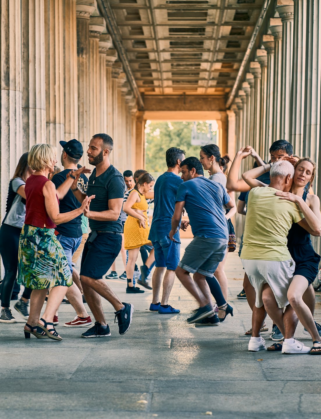 Adulti che ballano la salsa sotto un colonnato di pietra.